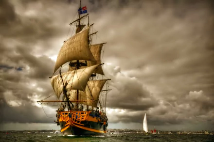 A majestic sailing ship with billowing sails navigates through a dramatic ocean scene under a cloudy sky, creating an impressive HD desktop wallpaper.