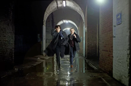 Dr. Watson and Sherlock Holmes, portrayed by Martin Freeman and Benedict Cumberbatch, dash through a dimly lit corridor in this 4K Ultra HD wallpaper from the TV series Sherlock.