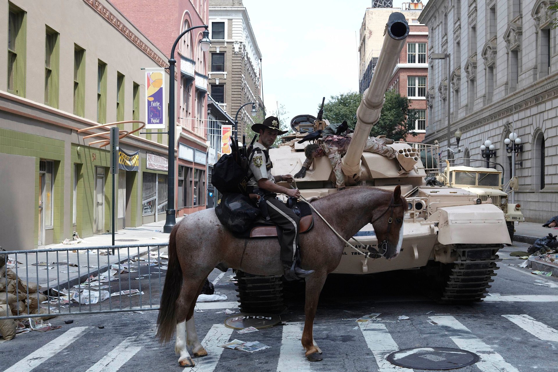 HD PC desktop wallpaper featuring Rick Grimes (Andrew Lincoln) from The Walking Dead, showing him on horseback in an urban street setting with a military tank.