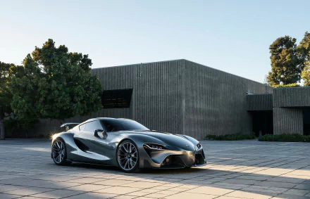 Silver Toyota FT-1 supercar concept parked outdoors by a modern building, captured in high definition as a sleek, futuristic vehicle desktop wallpaper and background.