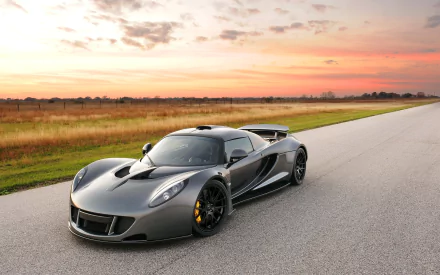 A sleek silver Hennessey Venom GT supercar parked on an empty road under a vibrant sunset, showcasing its aerodynamic design and powerful stance. Perfect HD wallpaper for car enthusiasts.