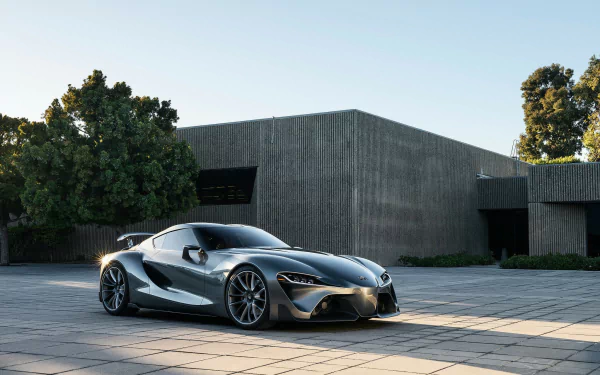 Silver Toyota FT-1 supercar concept parked outdoors by a modern building, captured in high definition as a sleek, futuristic vehicle desktop wallpaper and background.
