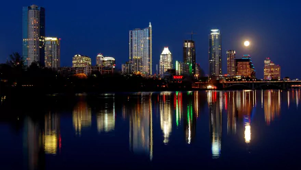 HD PC desktop wallpaper background: Austin skyline at night, illuminated skyscrapers and full moon reflecting on a calm river — modern man-made cityscape.