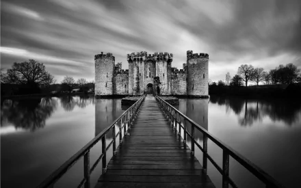 Black and white HD desktop wallpaper of Bodiam Castle, a historic man-made fortress reflected in calm waters under a dramatic sky.
