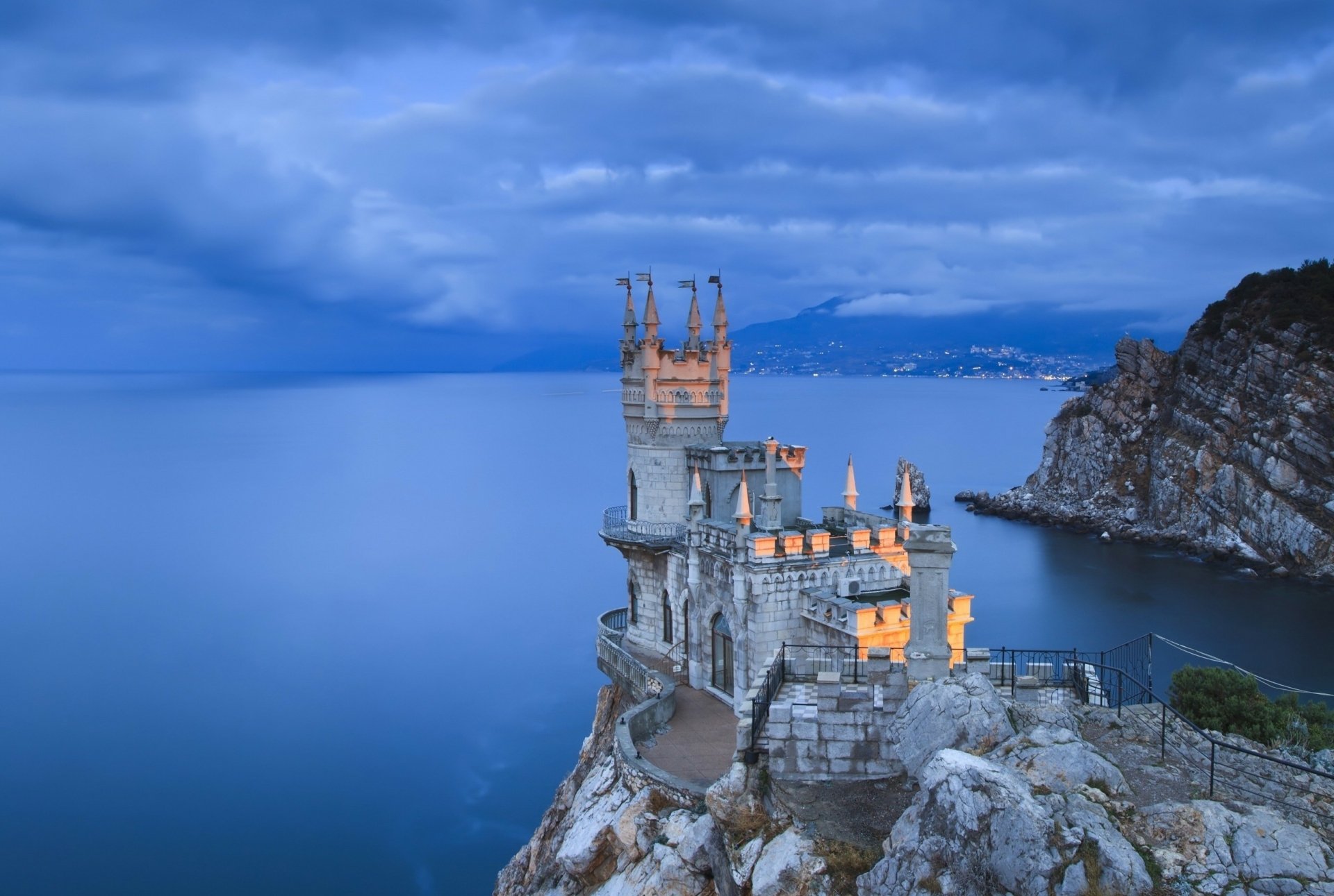 HD desktop wallpaper of the Swallow's Nest, a man-made castle perched on a cliff overlooking the Black Sea in Yalta, Russia, under a cloudy blue sky.
