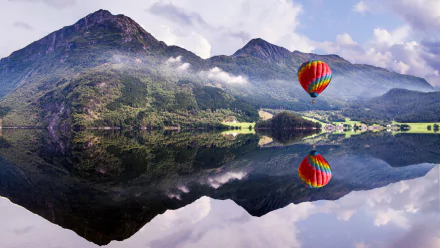 A vibrant hot air balloon soars above a serene lake, reflecting the surrounding mountains and lush landscape, creating a stunning HD desktop wallpaper.