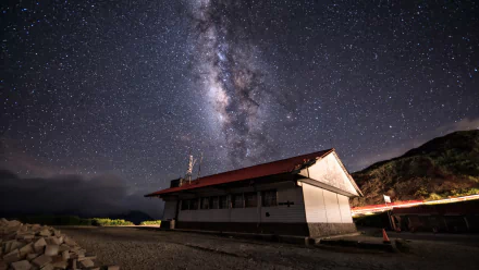 Sci‑Fi 4K Ultra HD PC desktop wallpaper: Milky Way arcing over an isolated coastal building, vivid galactic core and starfield bathing the night sky.