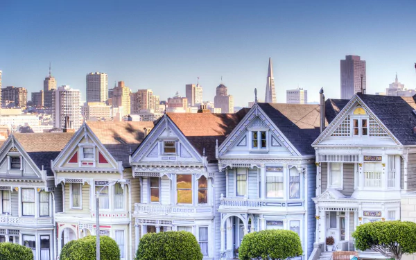 4K Ultra HD image of the Painted Ladies, iconic man-made Victorian houses in San Francisco, set against the city skyline at sunset.