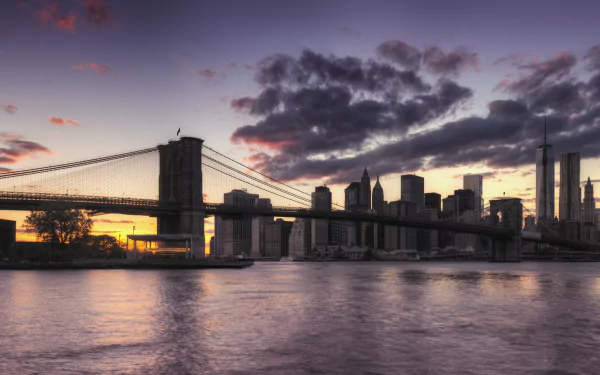 4K Ultra HD PC desktop wallpaper showing Brooklyn Bridge and Manhattan skyline at night in New York, man-made lights reflecting on the East River.