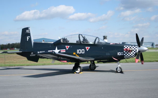 Military Beechcraft T-6 Texan II trainer parked on a tarmac under a blue sky — HD PC desktop wallpaper/background.