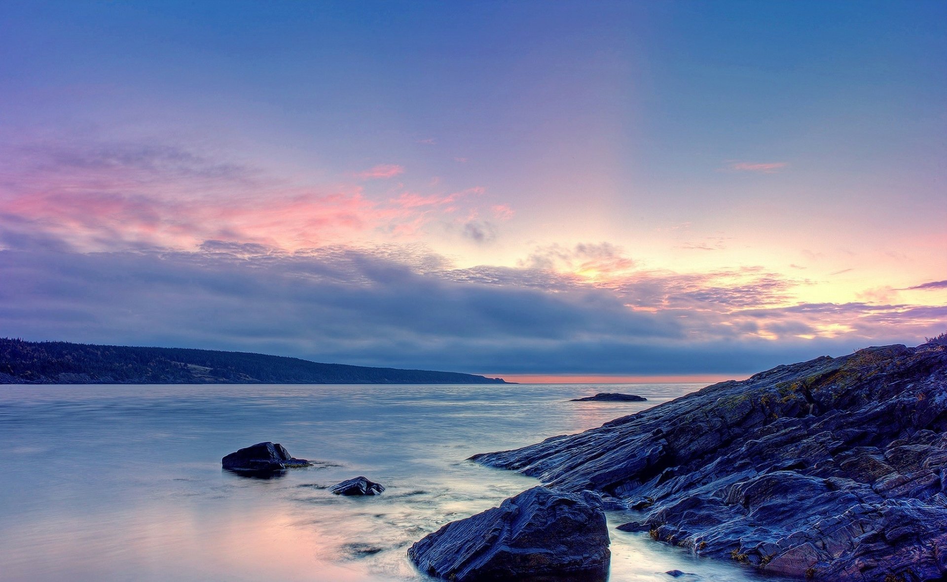 HD PC desktop wallpaper and background, a tranquil seashore nature scene with rocky foreground, calm water and pastel clouds at sunset.