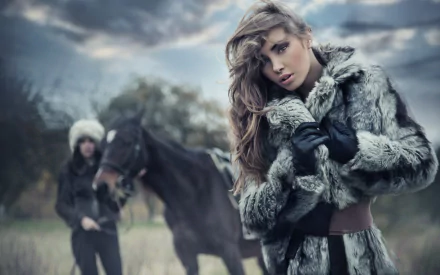 HD PC desktop wallpaper featuring a woman model in a fur coat posing in a moody outdoor setting with another person and a horse blurred in the background.