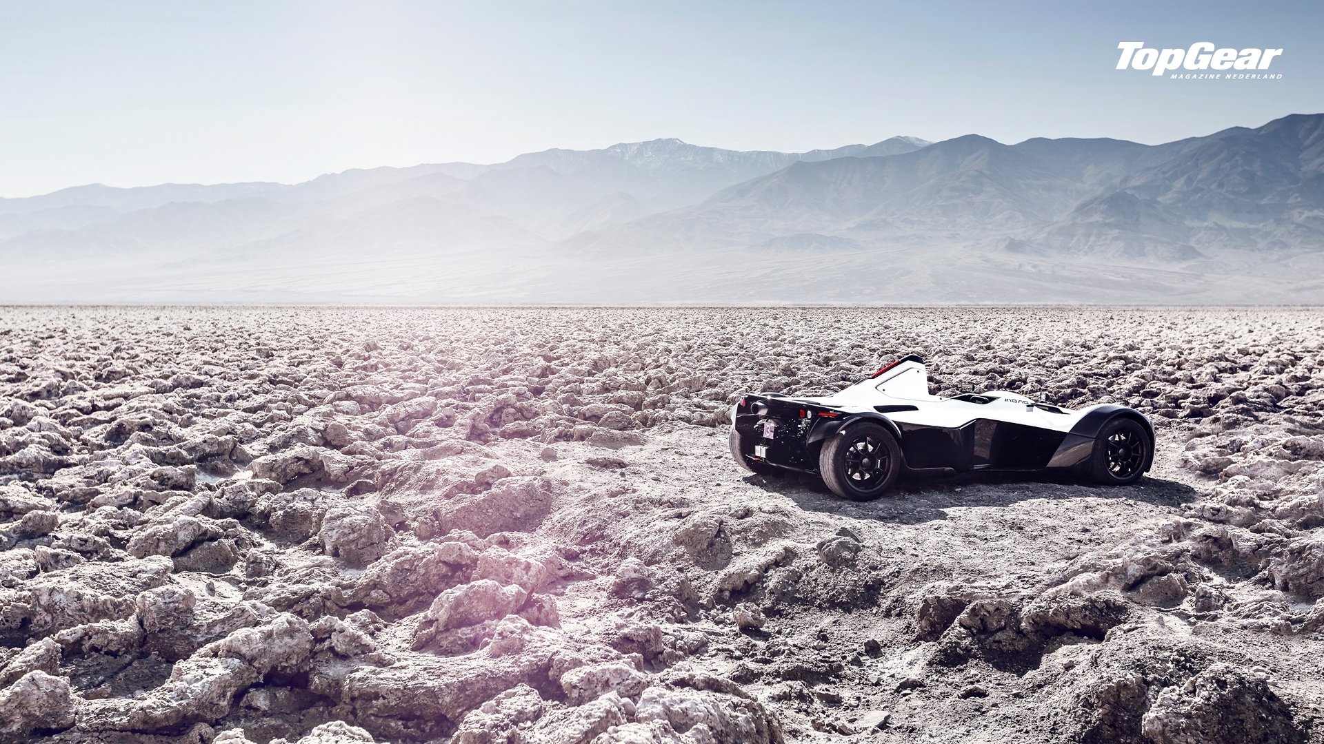 HD desktop wallpaper featuring the BAC Mono race car on a cracked desert landscape, showcased in a Top Gear TV show scene with mountains in the background.