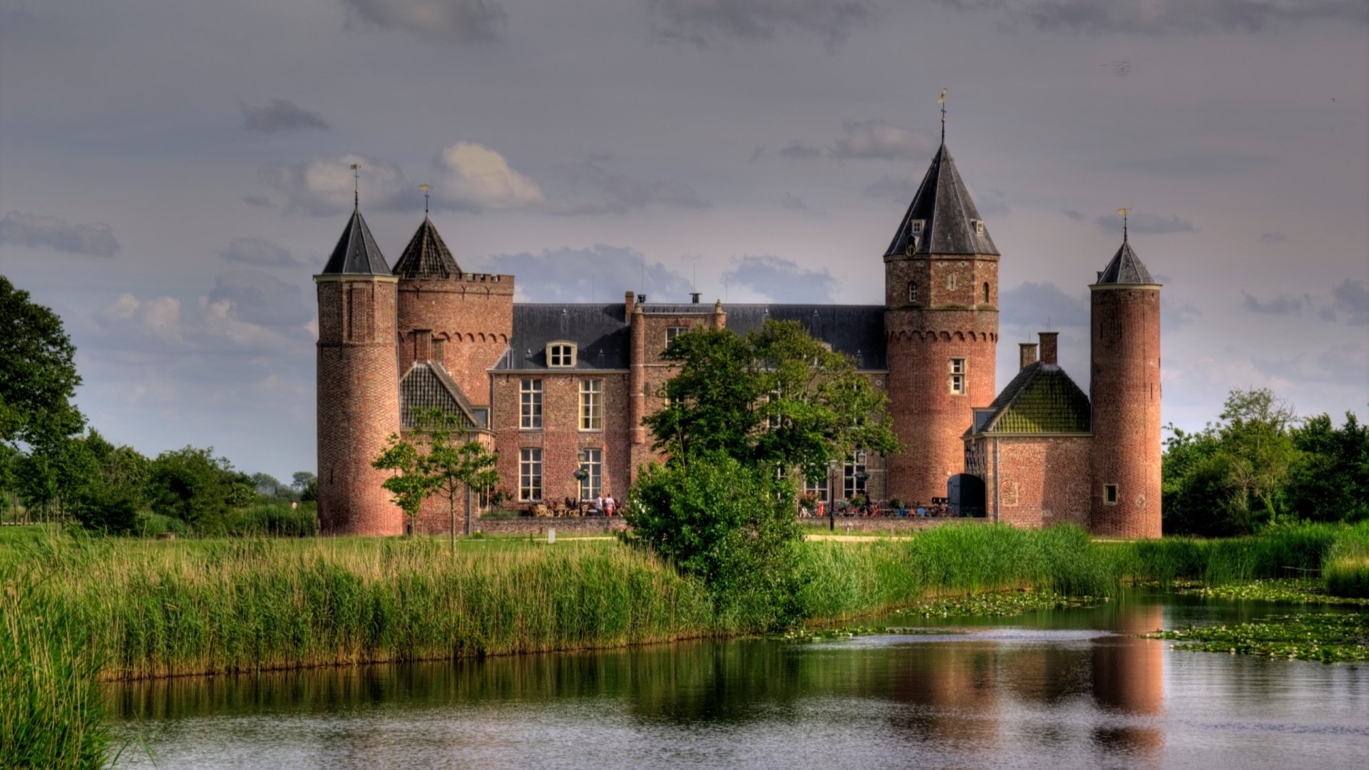 HD desktop wallpaper featuring the man-made Westhove Castle with its towers reflected in a calm moat under a cloudy sky.