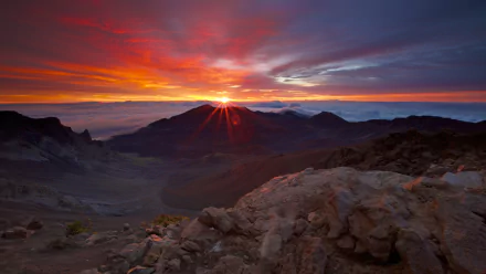 A vibrant sunrise illuminates the mountain landscape, casting warm hues across the sky. This breathtaking nature scene serves as a stunning HD desktop wallpaper and background.