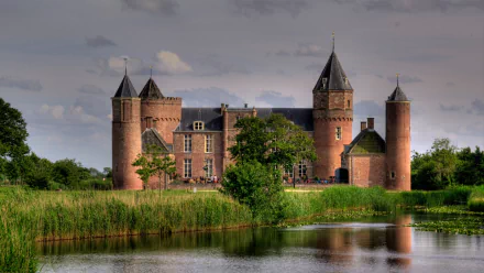 HD desktop wallpaper featuring the man-made Westhove Castle with its towers reflected in a calm moat under a cloudy sky.