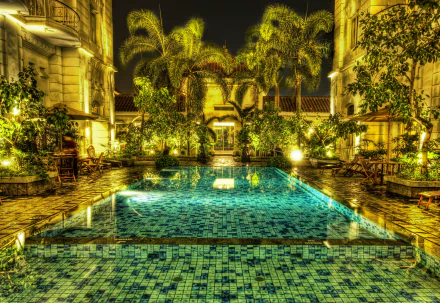 HD image of a luminous, mosaic-tiled pool in Jakarta, Indonesia, surrounded by palm trees and elegant colonial architecture, captured in HDR.