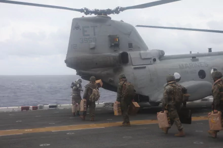 Marines prepare to board a Boeing Vertol CH-46 Sea Knight helicopter on a naval ship deck, showcasing military aviation and vehicle operations.