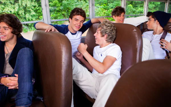 A vibrant HD wallpaper featuring One Direction members enjoying a casual moment together on a bus, surrounded by lush greenery, capturing the essence of their camaraderie.