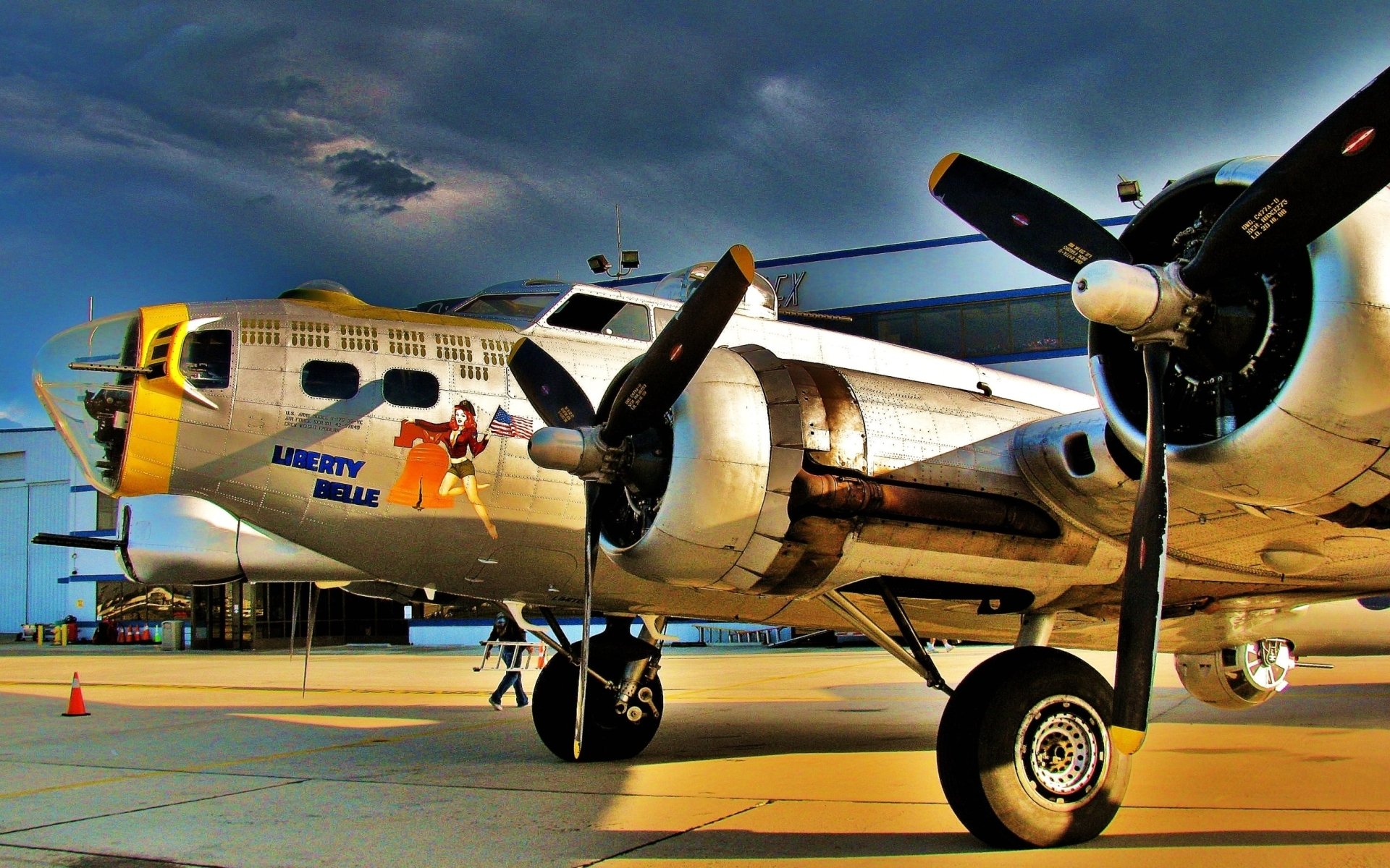 HD PC desktop wallpaper/background of a vintage military bomber on a tarmac at sunset, close-up of propellers and colorful aircraft nose art.
