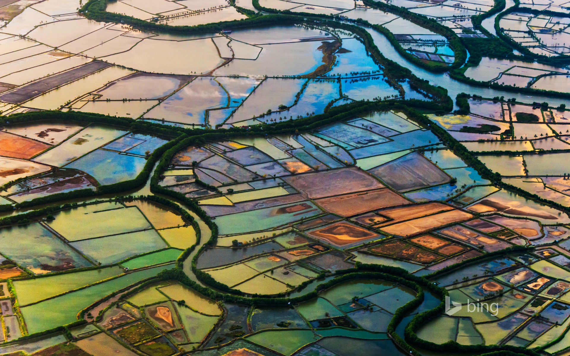 Aerial view of vibrant farmland with winding waterways, showcasing a colorful mosaic of fields and nature's beauty. This HD image serves as a captivating desktop wallpaper and background.