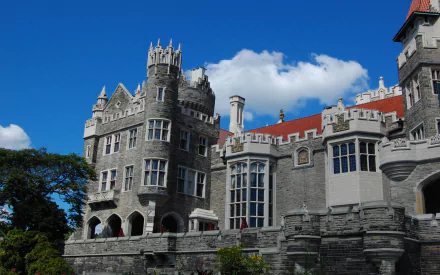 HD PC desktop wallpaper of Casa Loma — a man-made stone castle with turrets and red roofs against a vivid blue sky, architectural background.