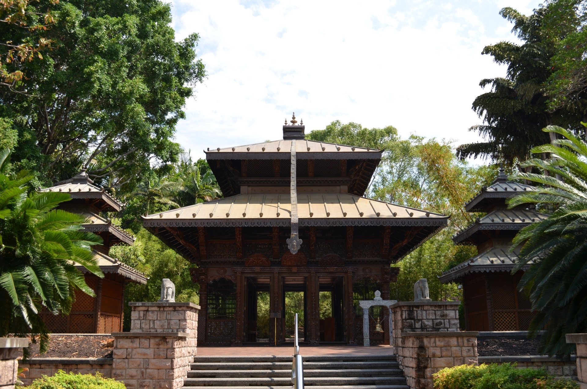 HD desktop wallpaper showing a man-made Nepalese Buddhist pagoda temple in Brisbane, Australia, framed by lush trees.