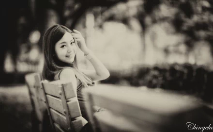 Black and white HD desktop wallpaper featuring a vintage image of an Asian woman seated on a wooden bench, smiling while looking back over her shoulder in an outdoor setting.