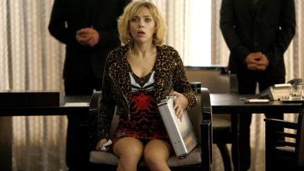Scarlett Johansson in a scene from the movie Lucy, holding a briefcase and looking startled, featured in a 4K Ultra HD PC desktop wallpaper.