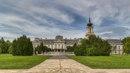 Man-made Festetics Palace seen from a stone pathway, lawns and trees under a dramatic sky — 2K Quad HD PC desktop wallpaper/background.