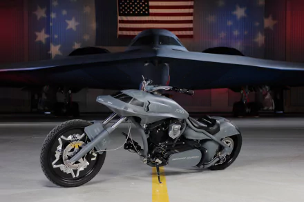 A sleek motorcycle in the foreground, with the Northrop Grumman B-2 Spirit stealth aircraft and an American flag in the background, showcasing military aviation heritage.