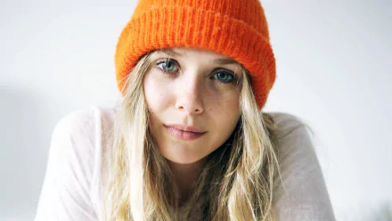 A close-up of Elizabeth Olsen wearing an orange beanie, showcasing her natural beauty. This HD image serves as an engaging desktop wallpaper or background.