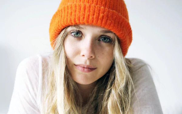 A close-up of Elizabeth Olsen wearing an orange beanie, showcasing her natural beauty. This HD image serves as an engaging desktop wallpaper or background.