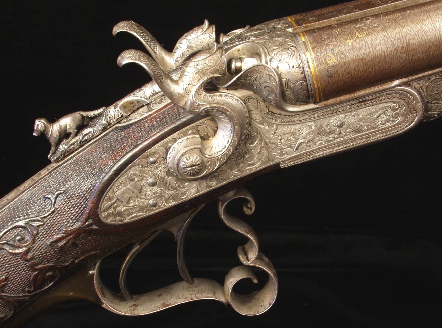 Close-up HD desktop wallpaper of an intricately engraved man-made shotgun with ornate metalwork and detailed craftsmanship on a dark background.
