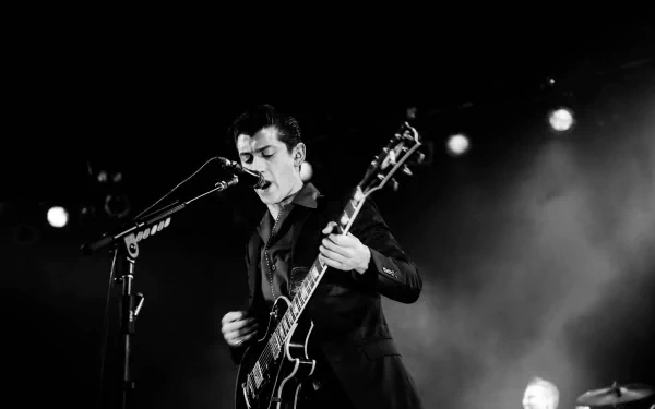 A captivating black and white image of the Arctic Monkeys' lead singer performing passionately with an electric guitar, set against a dramatic stage backdrop.