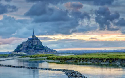 HD PC desktop wallpaper background: Mont Saint-Michel religious abbey-castle on a tidal island at sunset, dramatic clouds and reflective water.