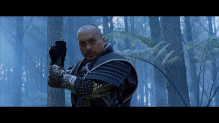 A character from the movie The Last Samurai, dressed in traditional armor, stands poised with a sword in a misty forest, showcasing the film's dramatic atmosphere. HD desktop wallpaper.