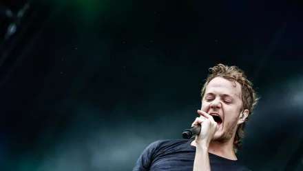 A dynamic 4K Ultra HD wallpaper featuring a performer passionately singing on stage, representing the energy and spirit of Imagine Dragons.