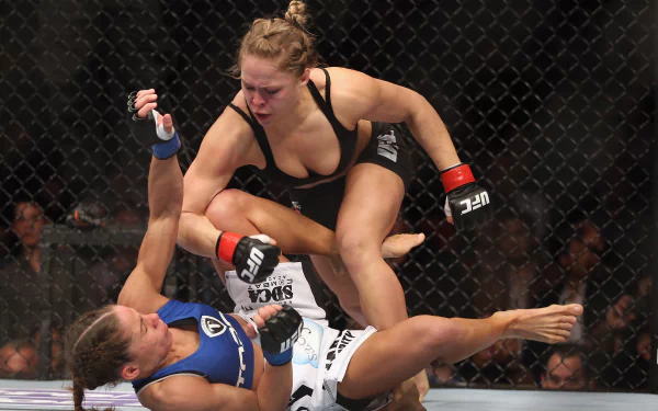 HD sports wallpaper featuring Ronda Rousey in action during a UFC fight inside the octagon, showcasing intense mixed martial arts competition.