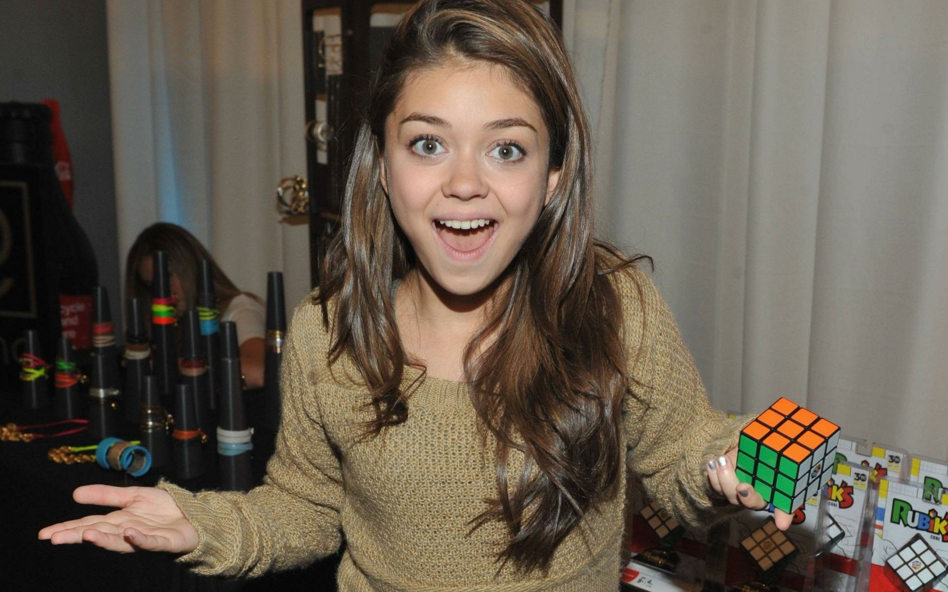 HD wallpaper featuring a cheerful young person from Modern Family, holding a Rubik's Cube with a surprise expression.