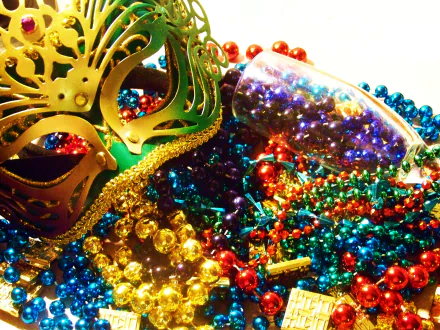 A vibrant assortment of colorful Mardi Gras beads and a festive mask, creating an inviting holiday atmosphere, serves as a lively HD desktop wallpaper and background.