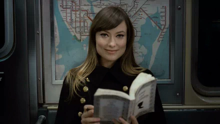 HD desktop wallpaper of a woman in a dark coat reading a book on a subway, film still from the movie The Longest Week.