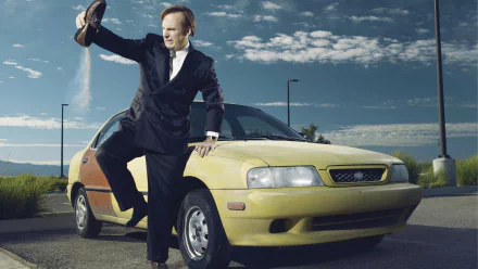 HD desktop wallpaper of Bob Odenkirk as Jimmy McGill from Better Call Saul, posing with his foot on a yellow car.