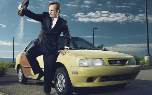 HD desktop wallpaper of Bob Odenkirk as Jimmy McGill from Better Call Saul, posing with his foot on a yellow car.