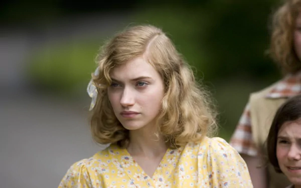 A captivating HD desktop wallpaper featuring actress Imogen Poots, showcasing her in a vintage-inspired yellow dress, standing amidst a lush, blurred background.