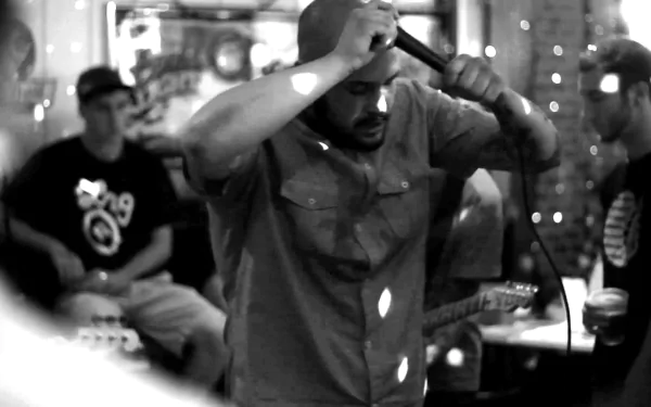 A dynamic black-and-white scene featuring a vocalist passionately performing on stage, surrounded by an engaged audience, capturing the essence of Being As An Ocean. HD desktop wallpaper.