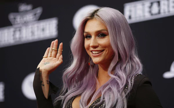 HD PC desktop wallpaper featuring musician Kesha with long lavender hair, smiling and waving against a dark, event-themed background.