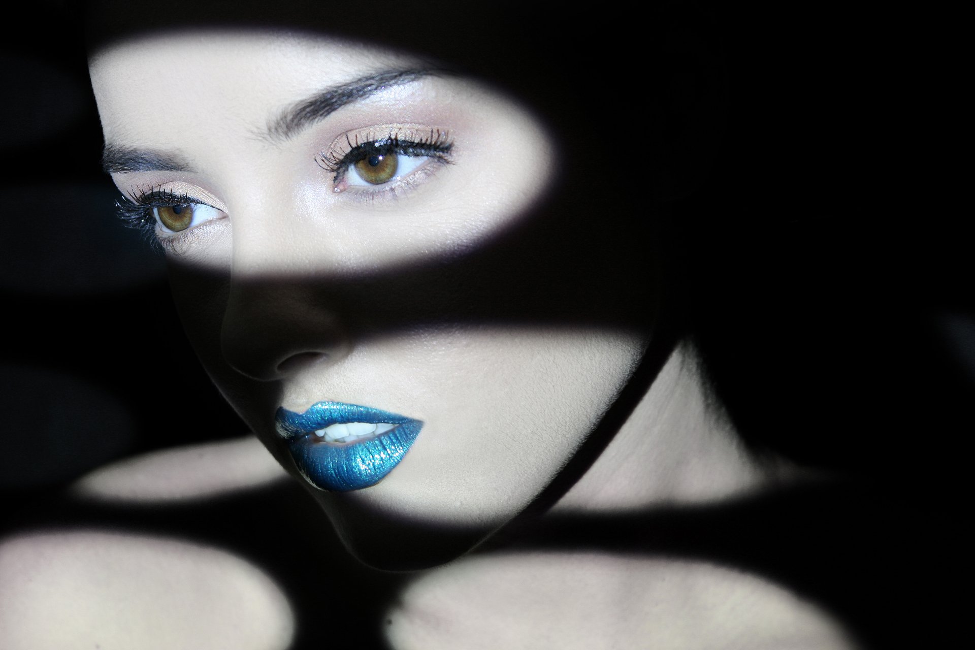 4K Ultra HD PC desktop wallpaper: close-up of a female model’s face with dramatic light and shadow, green eyes and metallic blue lips.