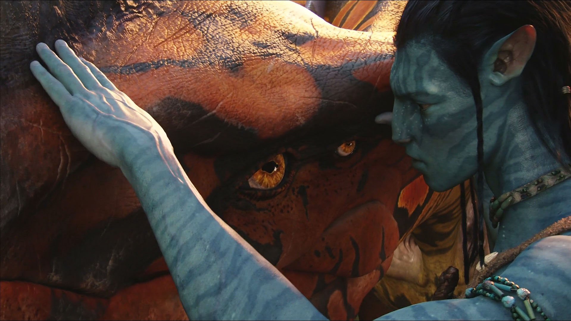 A captivating scene from the movie *Avatar*, featuring a blue-skinned character gently interacting with a large creature, set against a vivid, enchanting backdrop. HD desktop wallpaper.