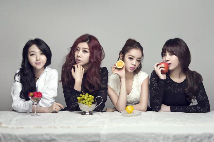 Four members of the K-pop group Girl's Day, each holding different fruits—grapes, an apple, and a lemon—are posed elegantly against a simple background in this vibrant 4K Ultra HD wallpaper.